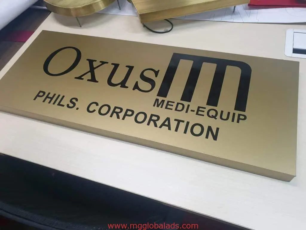 Acrylic desk signage for Oxus MEDI-EQUIP PHILS. CORPORATION in Makati, gold and black with M logo, by M&G Global Ads.