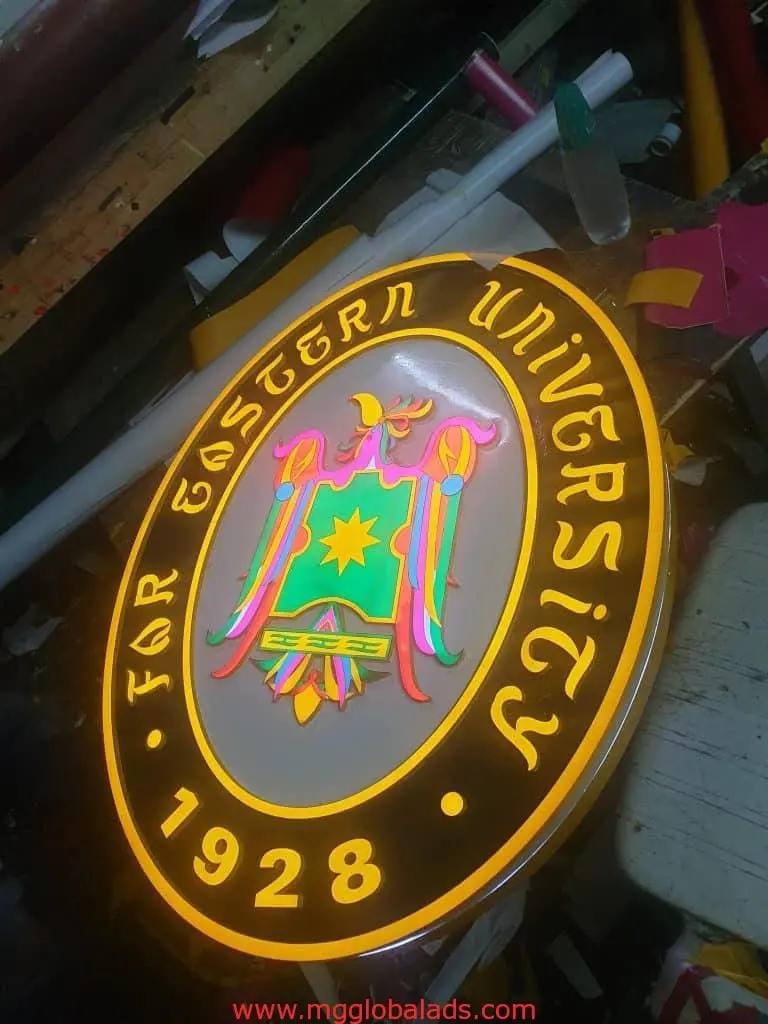 Round illuminated indoor signage for Far Eastern University in Quezon City, featuring 1928 seal by M&G Global Ads.