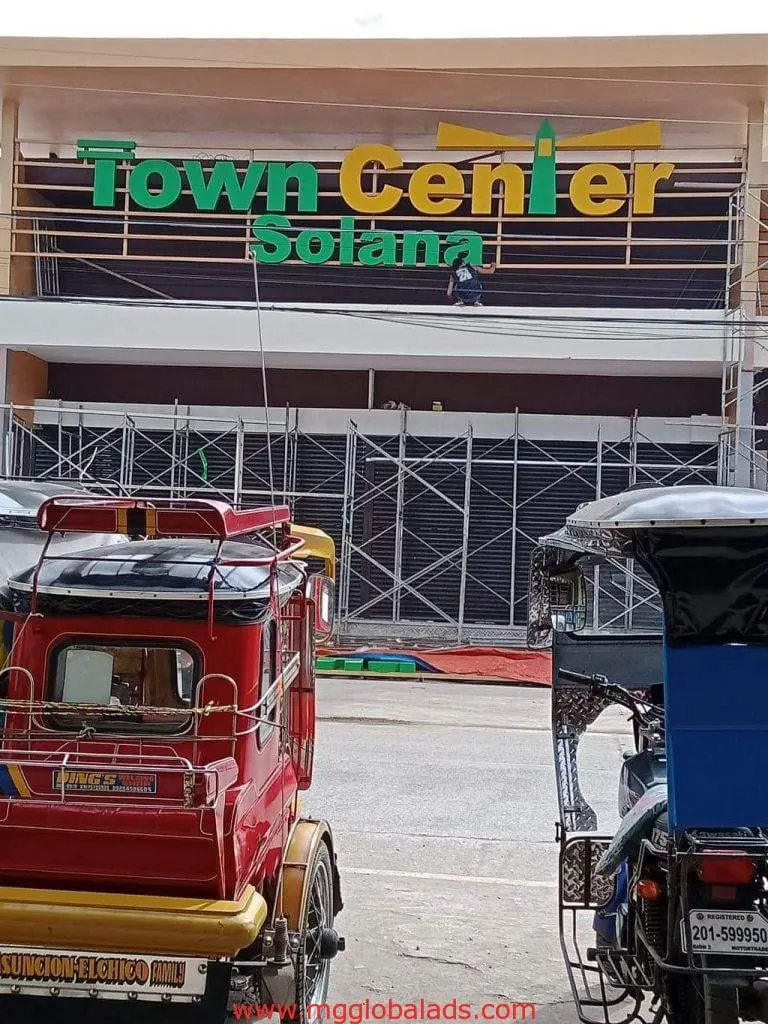Metallic building signage installation for Town Center Solana in Ortigas, with tricycles nearby. By M&G Global Ads.