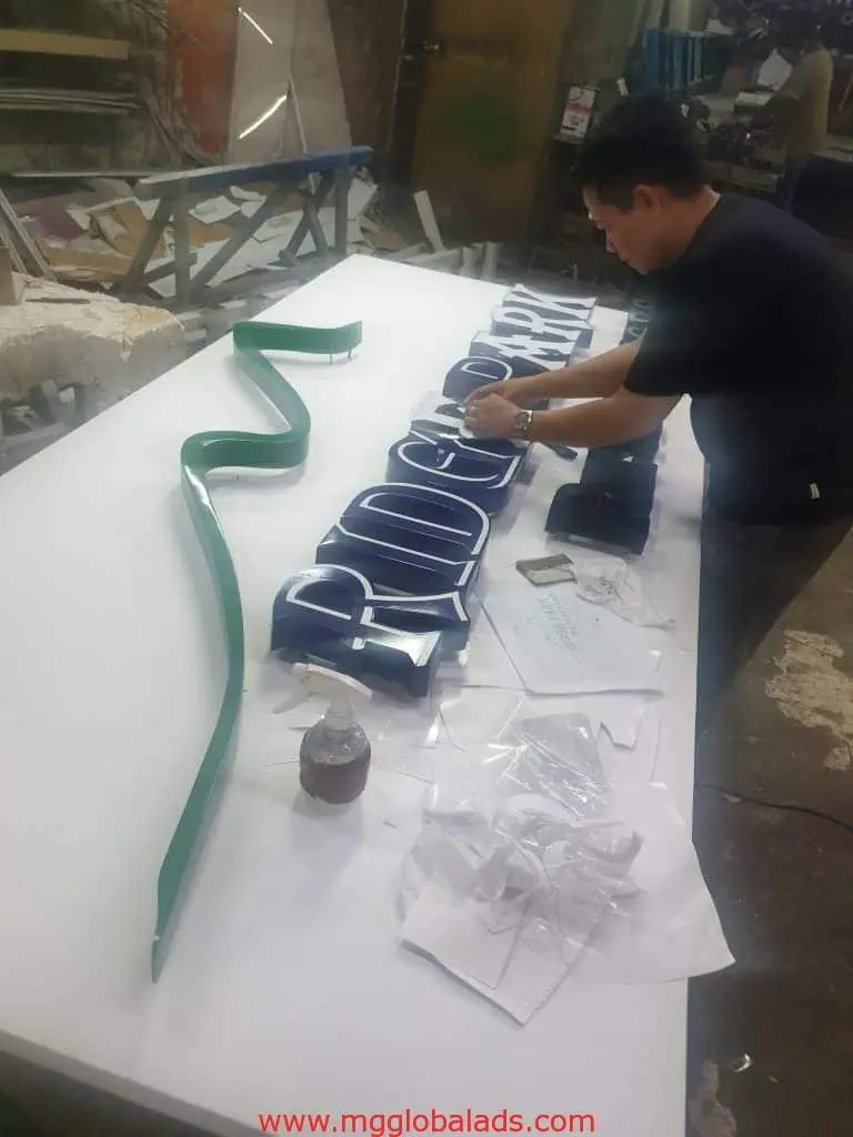 Indoor 3D signage assembly for Ridgepark in Ortigas, with green trim and tools on table, by M&G Global Ads.