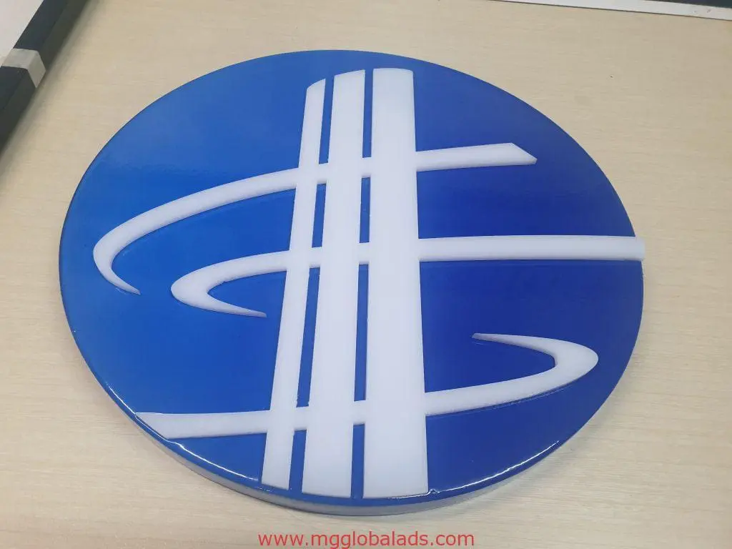 Round metallic logo signage with blue and white abstract design on wood, displayed in BGC by M&G Global Ads.