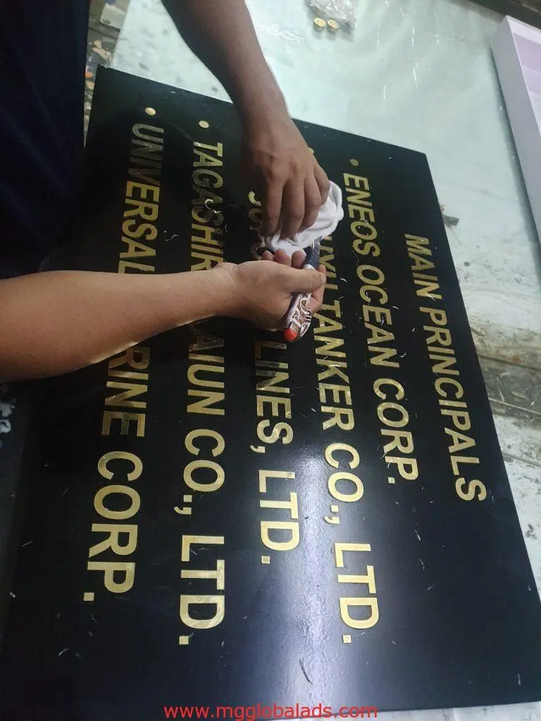 Outdoor directory signage for ENEOS OCEAN CORP. being cleaned in Makati, gold text on black panel by M&G Global Ads.