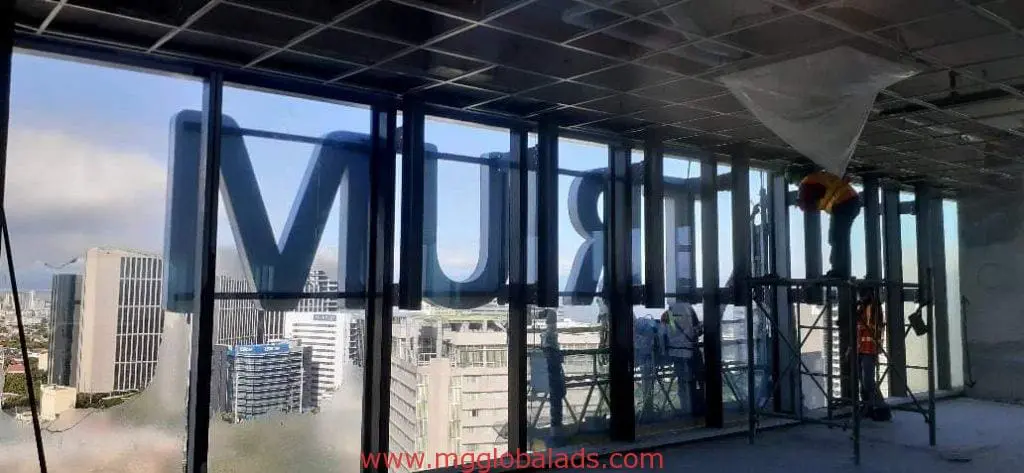 High-rise glass window signage for MURTR client, workers on scaffolding, Makati skyline view by M&G Global Ads.