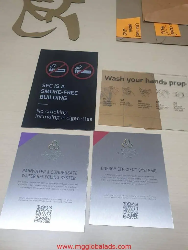 Acrylic indoor signage in Makati: building notice, hand-washing guide, rainwater and energy cards with QR codes by M&G Global Ads.