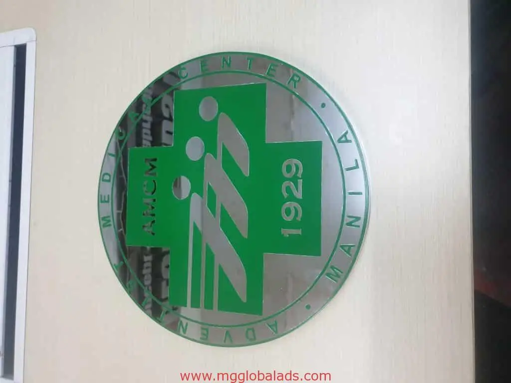Round metallic indoor signage for Adventist Medical Center Manila, Quezon City, with green emblem by M&G Global Ads.