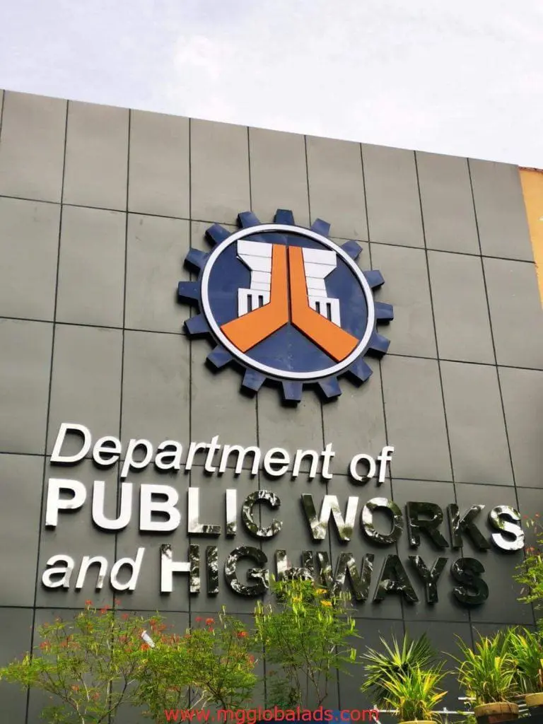 Department of Public Works and Highways outdoor signage in Quezon City, white letters on gray facade, by M&G Global Ads.