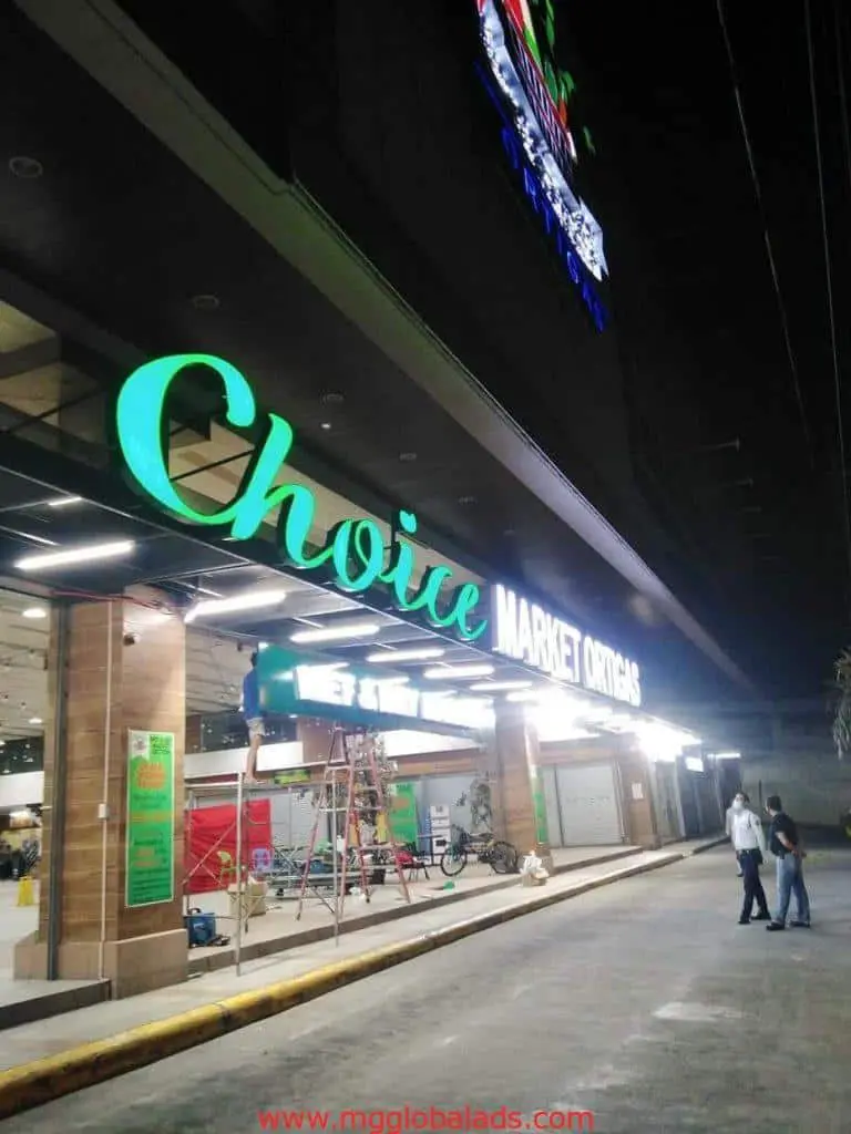 LED signage for Choice Market Ortigas supermarket in Makati, with people, ladder, and bicycles outside by M&G Global Ads.