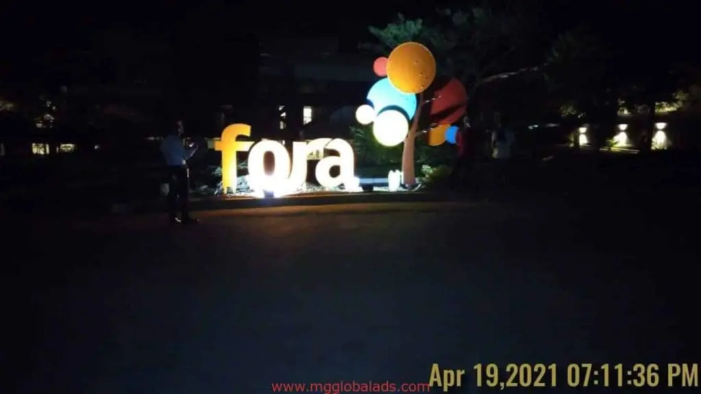 Illuminated pylon signage with colorful balloons at night, people nearby in Makati. Date: Apr 19, 2021. By M&G Global Ads.