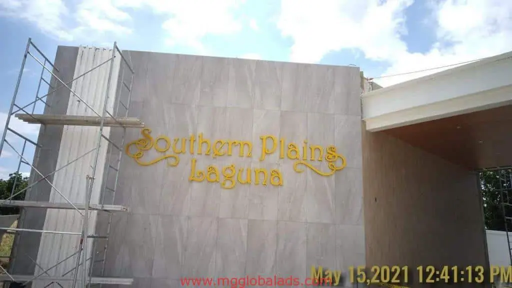 Acrylic building signage for Southern Plains Laguna on beige wall with scaffolding, Makati install by M&G Global Ads.