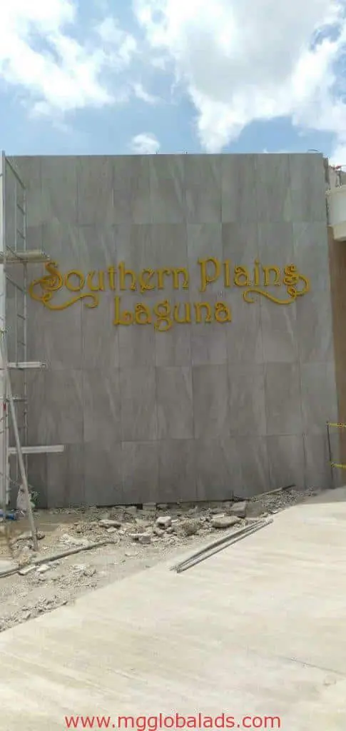 Southern Plains Laguna outdoor signage in decorative yellow letters on gray wall, construction site in Makati by M&G Global Ads.
