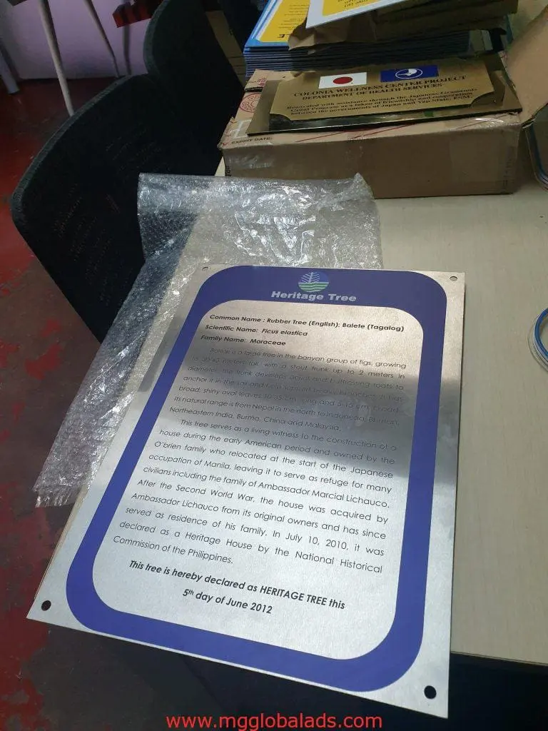 Heritage Tree metallic plaque signage on desk in Makati, with bubble wrap and chair, by M&G Global Ads.