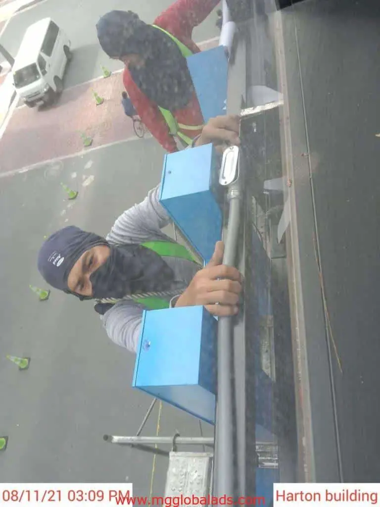 Building exterior window cleaning in Makati with visible commercial signage, view from inside by M&G Global Ads.