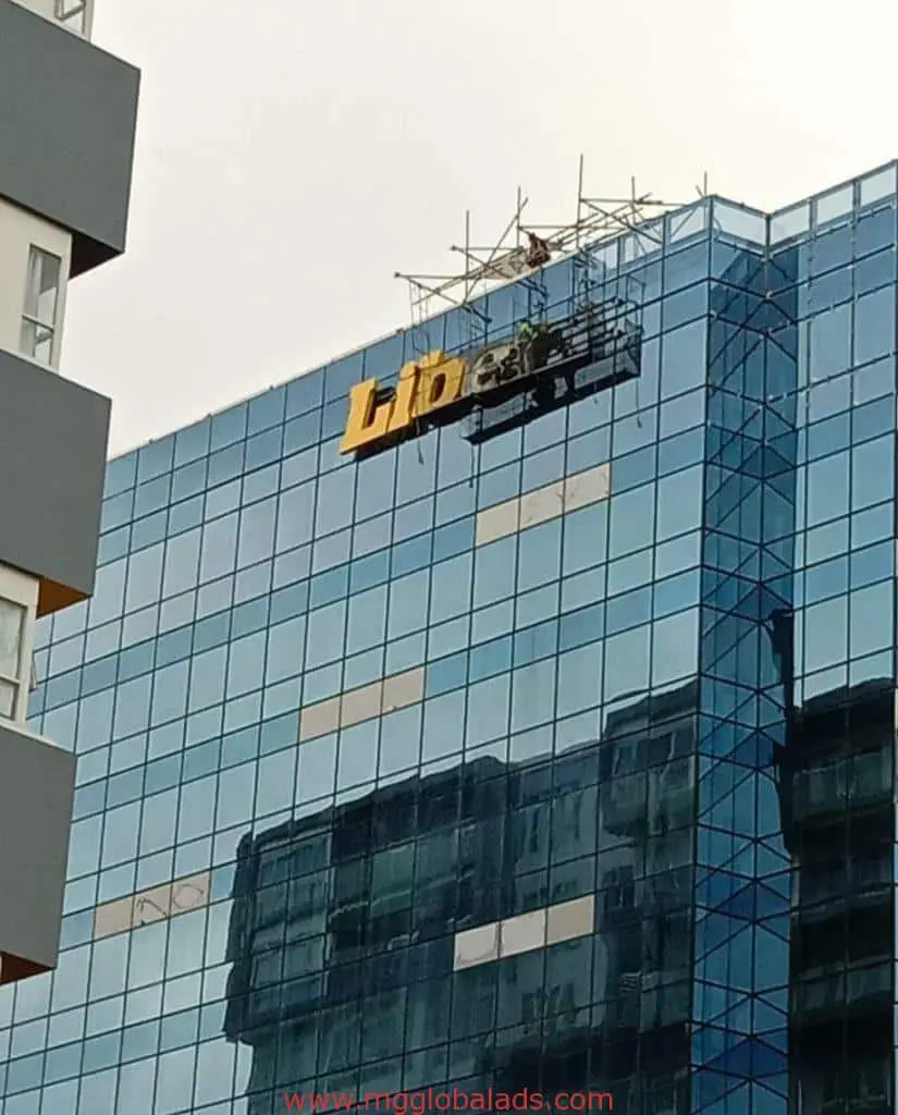 Metallic building signage installation for Lib on glass exterior of modern building in Makati by M&G Global Ads.