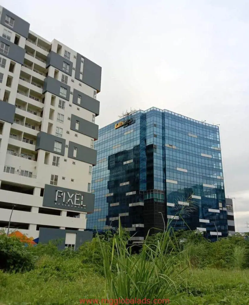 LED building signage PIXEL for residential client beside blue-glass office, green plants in Makati, by M&G Global Ads.