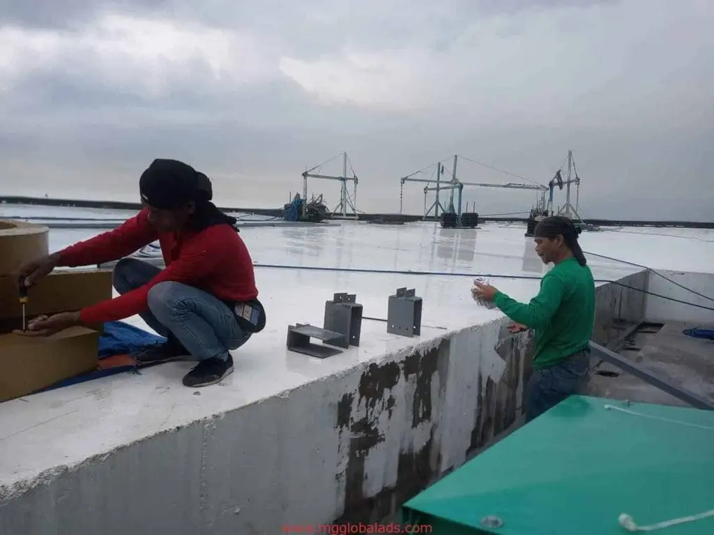 LED billboard signage installation on a rooftop in Mandaluyong, two workers with tools and cranes visible by M&G Global Ads.