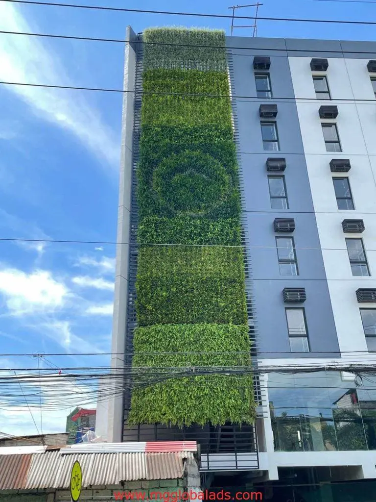 Greenwall and Moss Wall on a modern building with a vertical garden in Makati, windows, and AC units by M&G Global Ads.