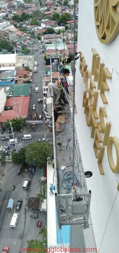 Hotel exterior gold aluminum signage installation for The Excelsior Hotel in Makati by M&G Global Ads. Workers on suspended platform.