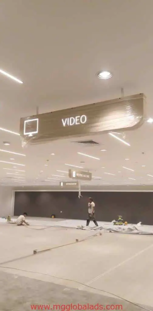 Ceiling signage install for VIDEO and MOVING IMAGE in unfinished Makati area, bright lights, by M&G Global Ads.