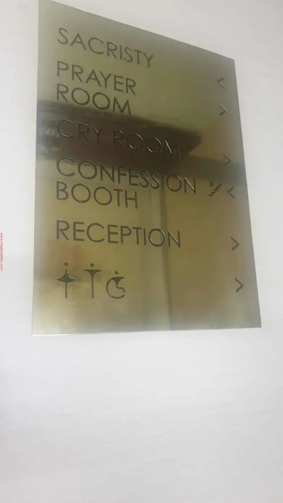 Gold acrylic directional church signage with arrows and religious icons in Makati, listing rooms. By M&G Global Ads.