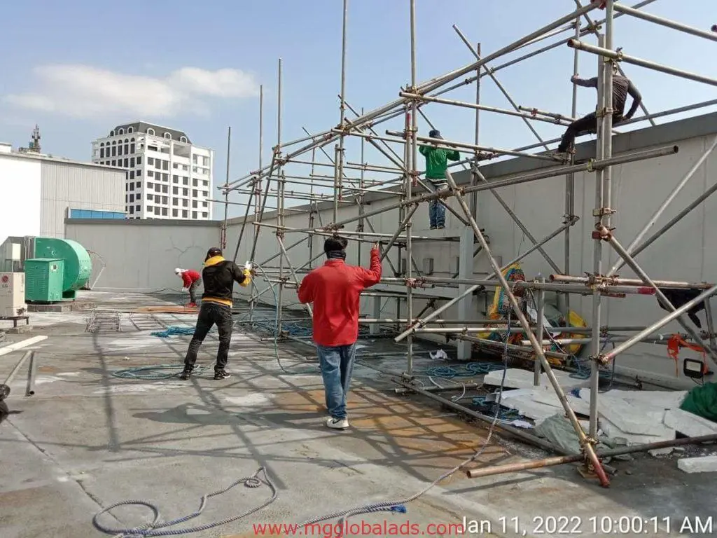 Acrylic signage installation on a rooftop in Makati, workers assembling scaffolding. Construction tools nearby. by M&G Global Ads.