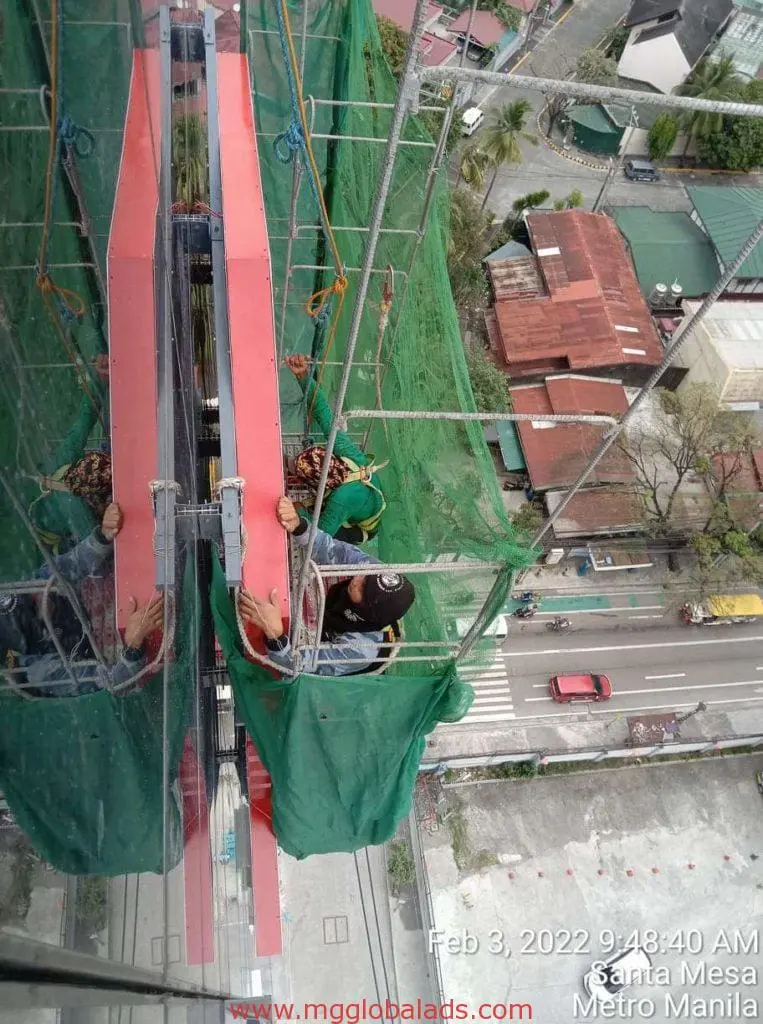 Billboard signage installation for client on red building, high above Makati street, by M&G Global Ads.