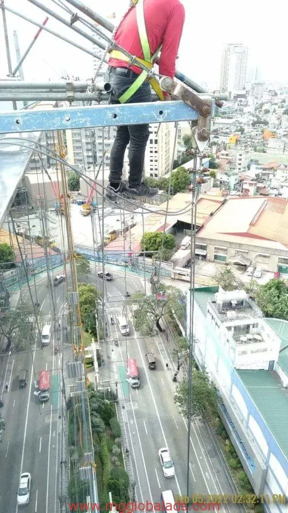 Metallic building signage installation for office tower client in Makati by M&G Global Ads. Construction worker on scaffolding.