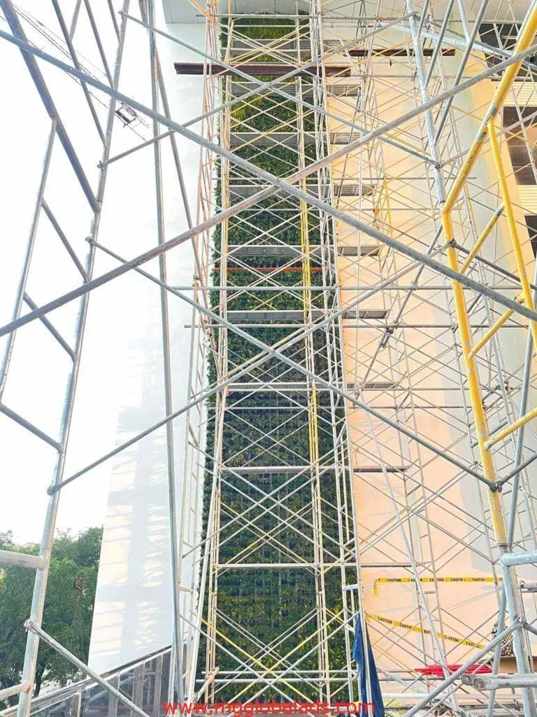 Scaffolding surrounds green wall install with illuminated building signage for client in Makati, by M&G Global Ads.