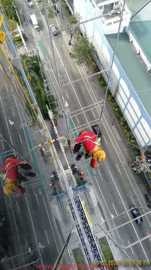 Metallic building signage cleaned on glass facade in Makati, with urban street view below, by M&G Global Ads.