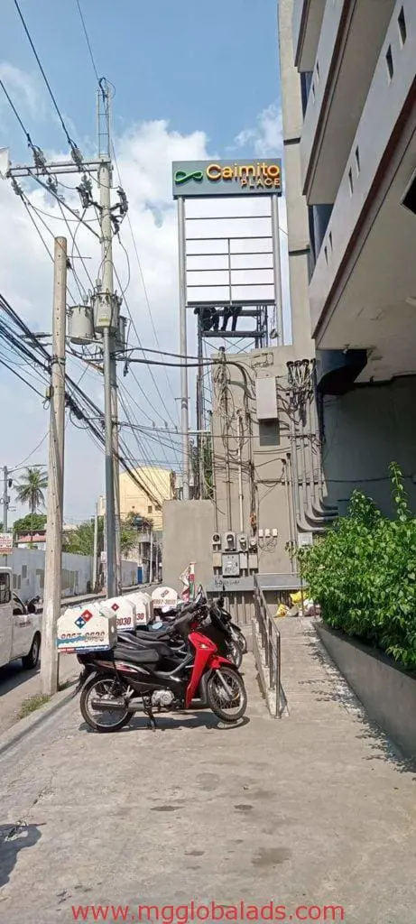 Outdoor Caimito building signage for Domino’s in Mandaluyong with parked motorcycles by M&G Global Ads.