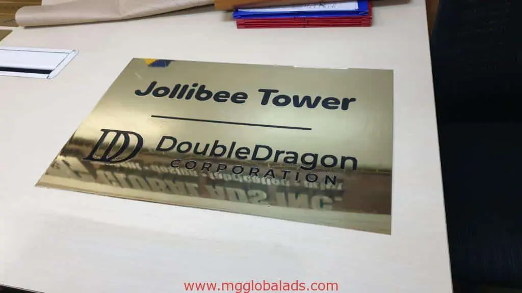 Acrylic desk signage for DoubleDragon Corporation at Jollibee Tower, Ortigas, with gold color and black text by M&G Global Ads.