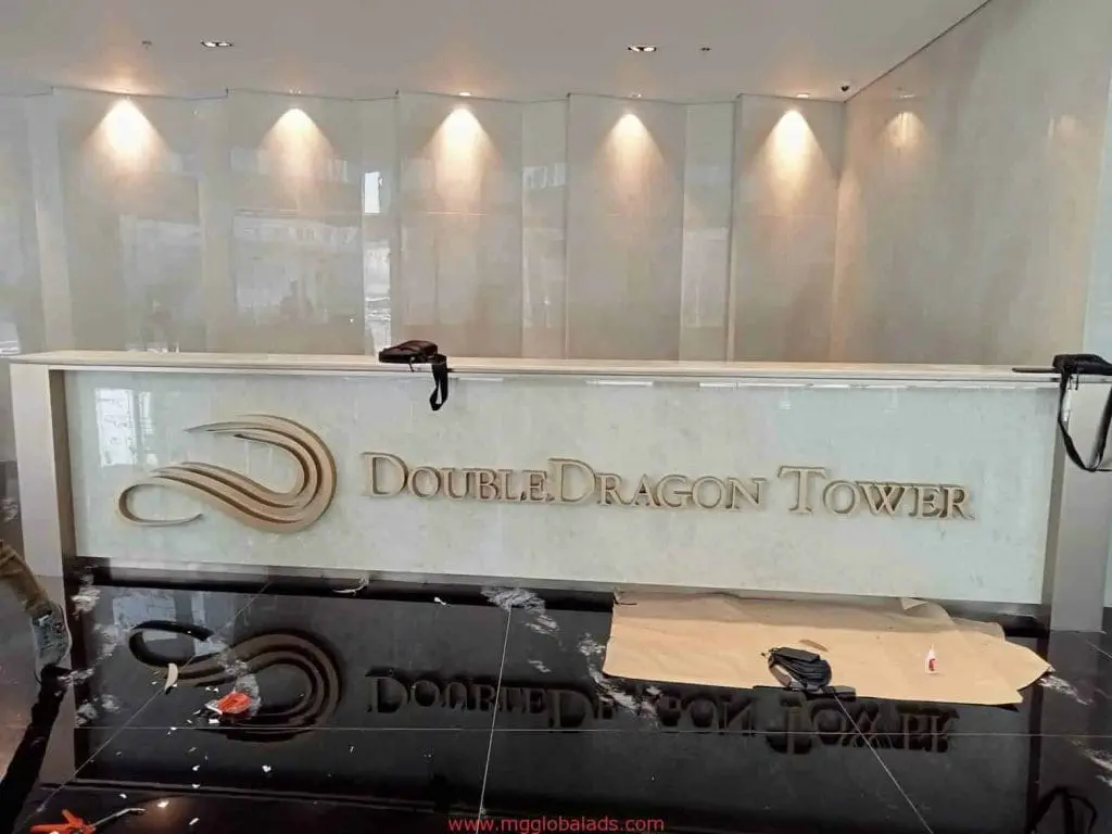 DoubleDragon Tower lobby signage, gold metal letters and logo at reception desk in BGC, by M&G Global Ads.