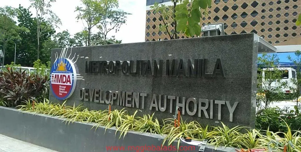 MMDA building signage in Quezon City, surrounded by plants and cityscape, by M&G Global Ads.