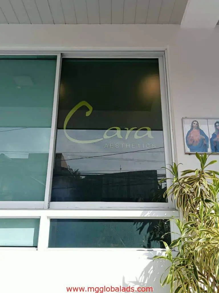 Cara Aesthetics glass window outdoor signage in Mandaluyong with potted plant and two religious images by M&G Global Ads.