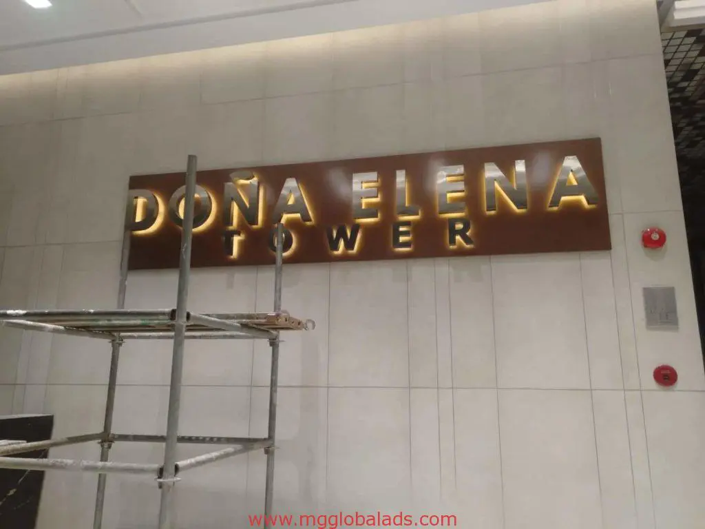 Building signage for DOÑA ELENA TOWER on a white wall, Makati location, scaffold in front, by M&G Global Ads.