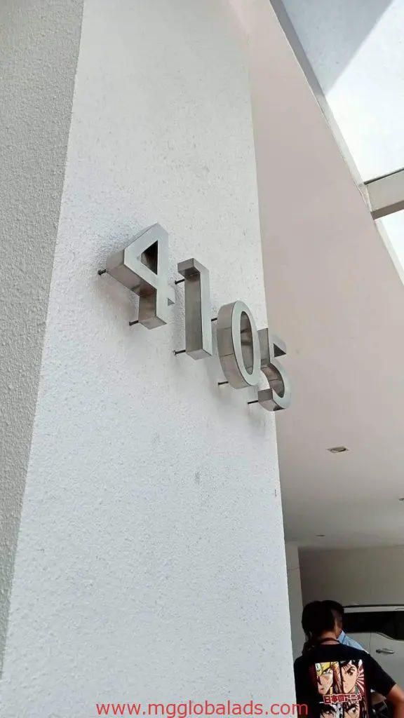 Metal address signage “4105” on white wall in Makati with person partially visible, outdoor installation by M&G Global Ads.