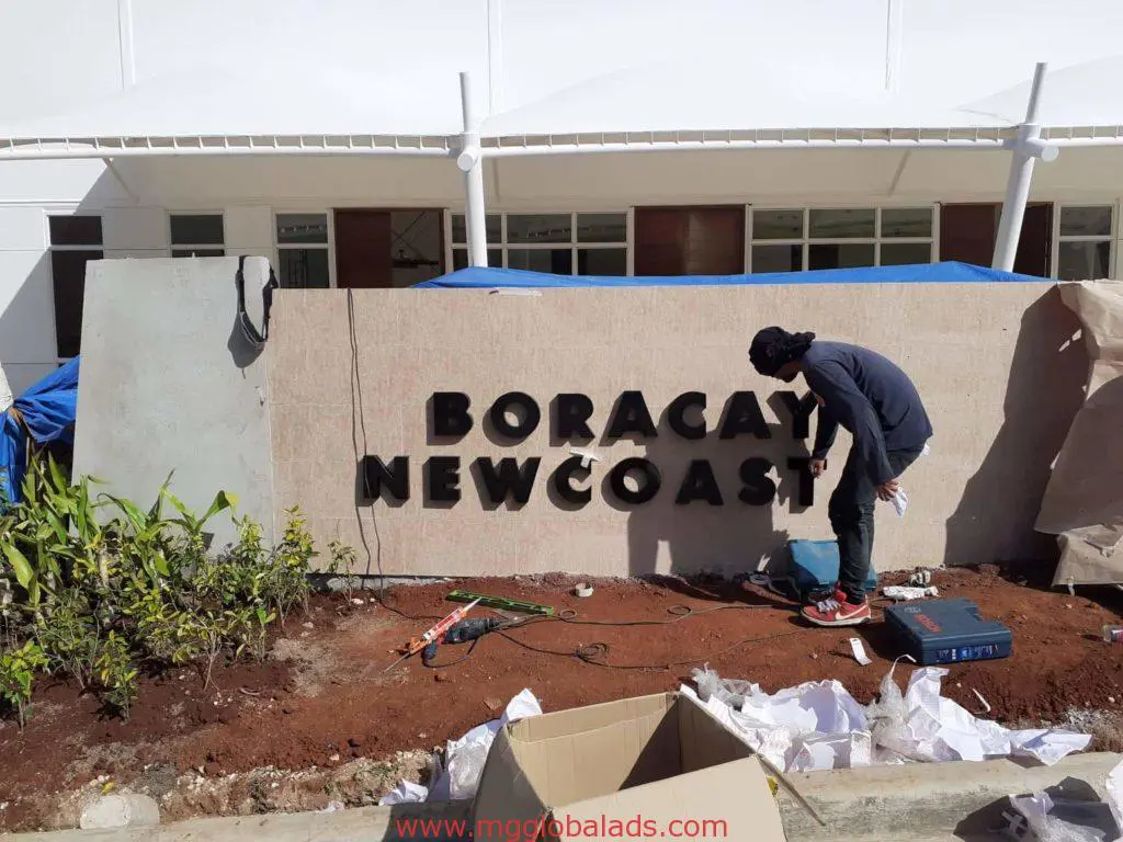 Outdoor building sign installation for Boracay Newcoast, Makati, with tools and open box nearby—by M&G Global Ads.