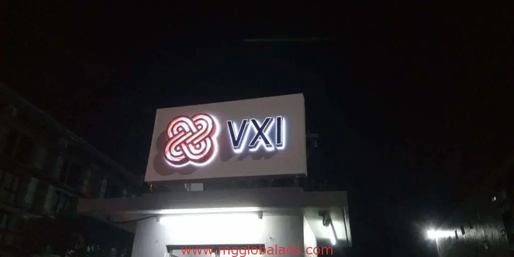 VXI rooftop outdoor signage with red and white logo in Makati at night, illuminated against a dark sky by M&G Global Ads.