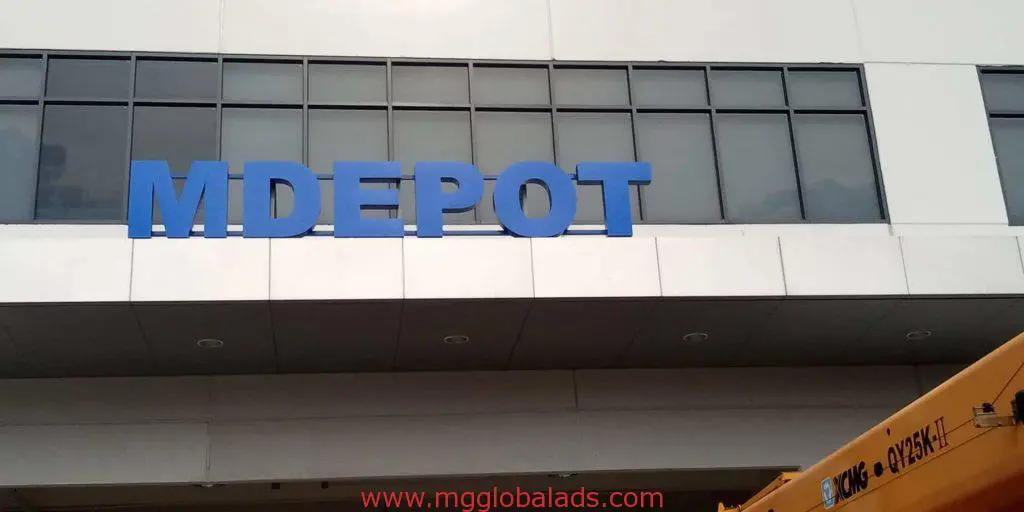 MDEPOT channel letter signage on building facade in Makati, blue metallic letters above windows, crane visible, by M&G Global Ads.