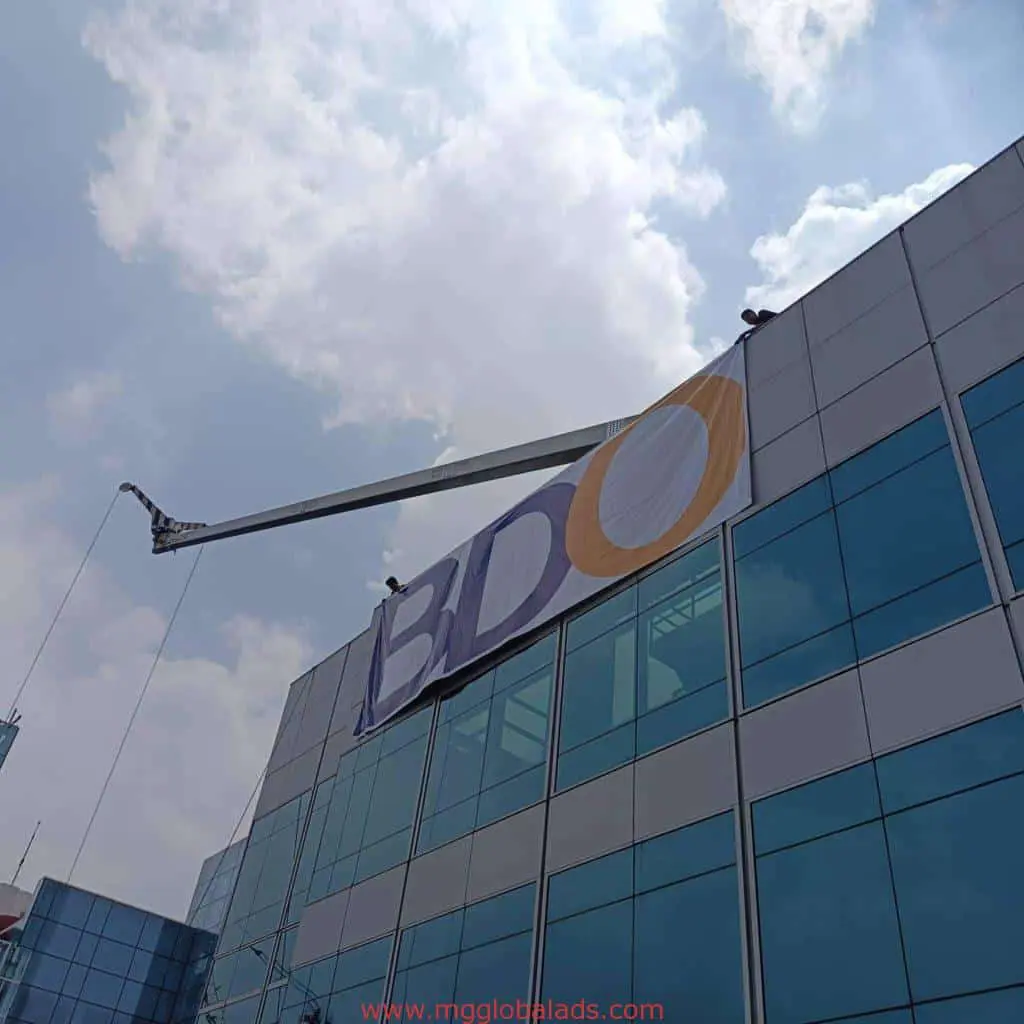 BDO building signage installation using crane on modern glass building in Makati by M&G Global Ads.