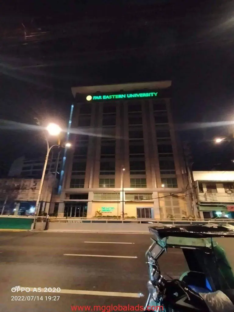 Green LED building signage for PMI Eastern University in Quezon City at night with a tricycle, by M&G Global Ads.