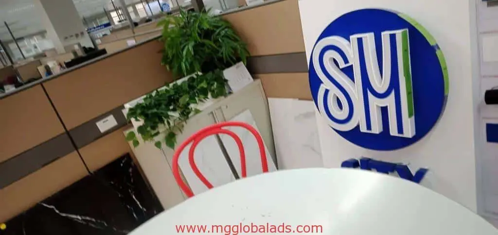 Metallic SM logo signage for SM client in Makati with red chair, white table, plants, and office cubicles by M&G Global Ads.