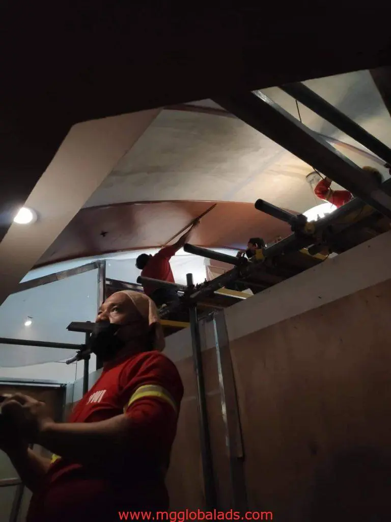 Workers painting a high ceiling on scaffold with indoor wayfinding signage in Quezon City, by M&G Global Ads.