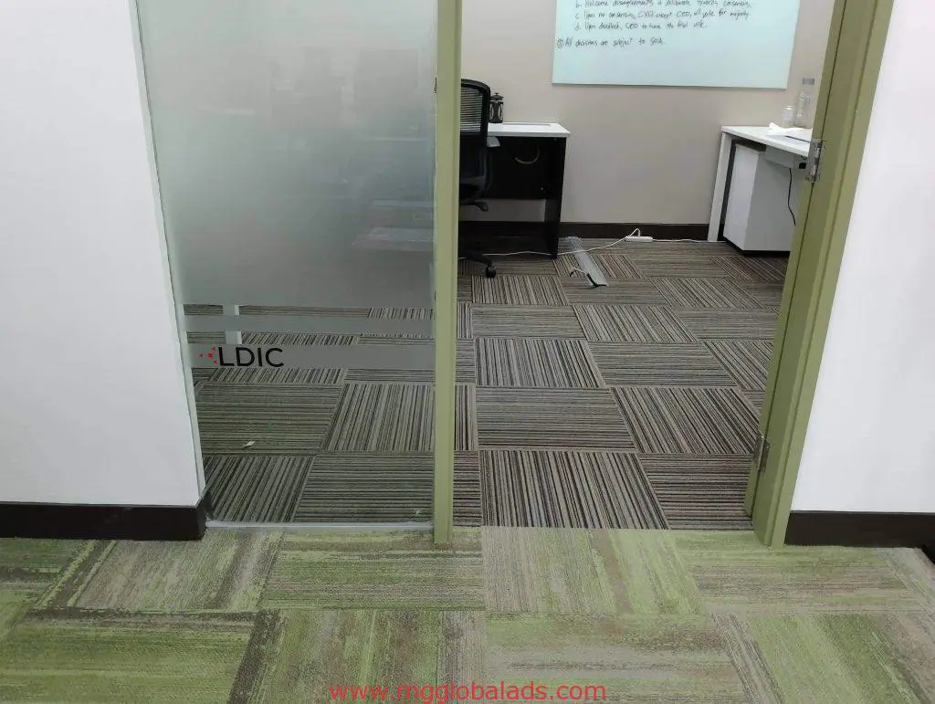Glass office door with LDIC acrylic signage at a Makati office, showing desk, chair, computer, whiteboard by M&G Global Ads.
