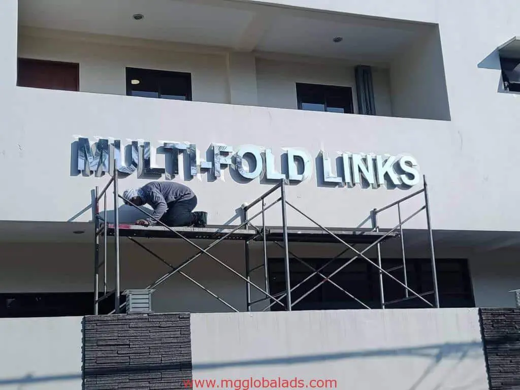 Metallic building signage for Multi-Fold Links installed by worker in Mandaluyong, outdoor sign project by M&G Global Ads.