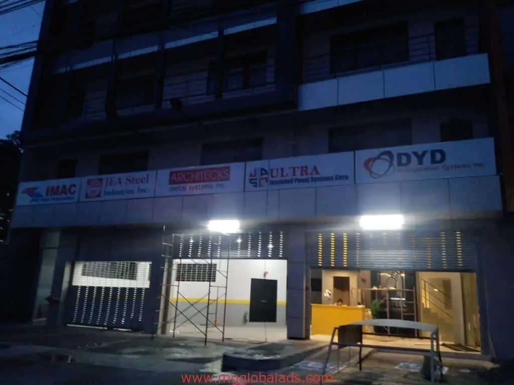 Illuminated outdoor LED signage on a commercial building in Makati at dusk, metal gates, reception area inside by M&G Global Ads.