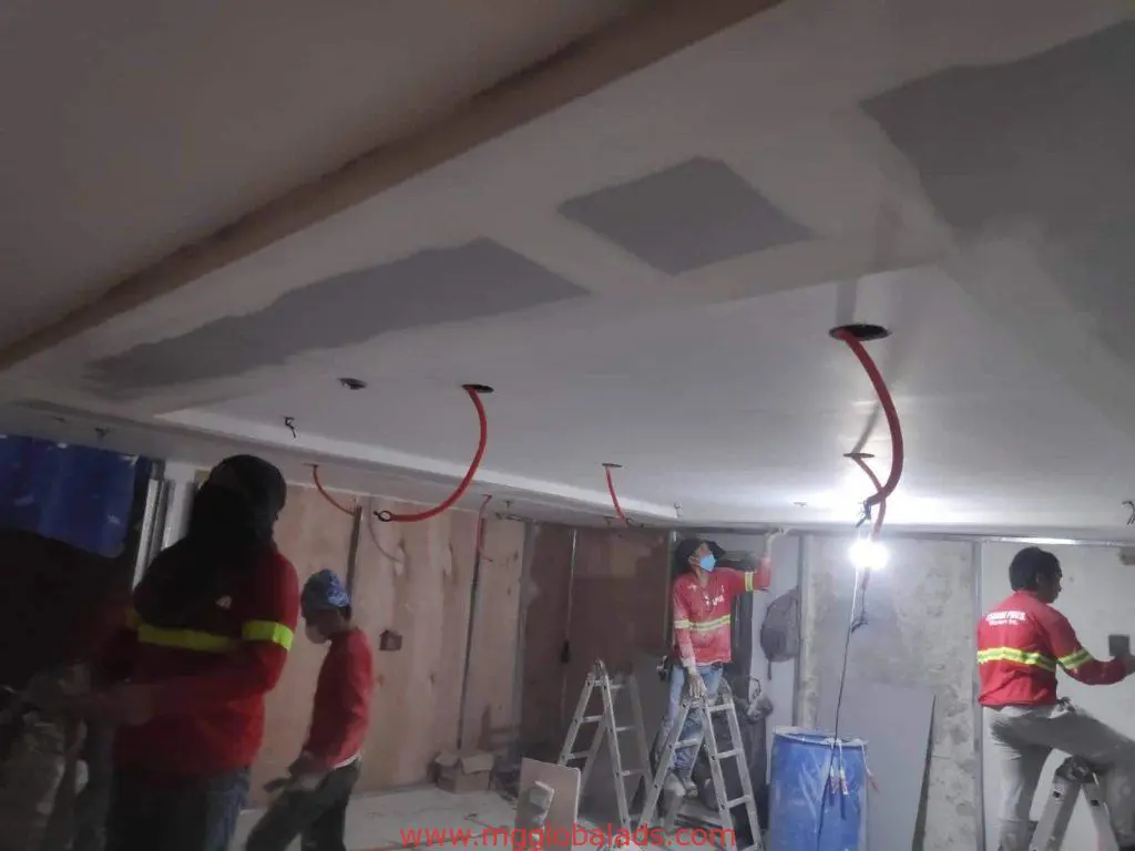 LED signage installation by four construction workers in Makati, indoor site with ladders and wiring, by M&G Global Ads.