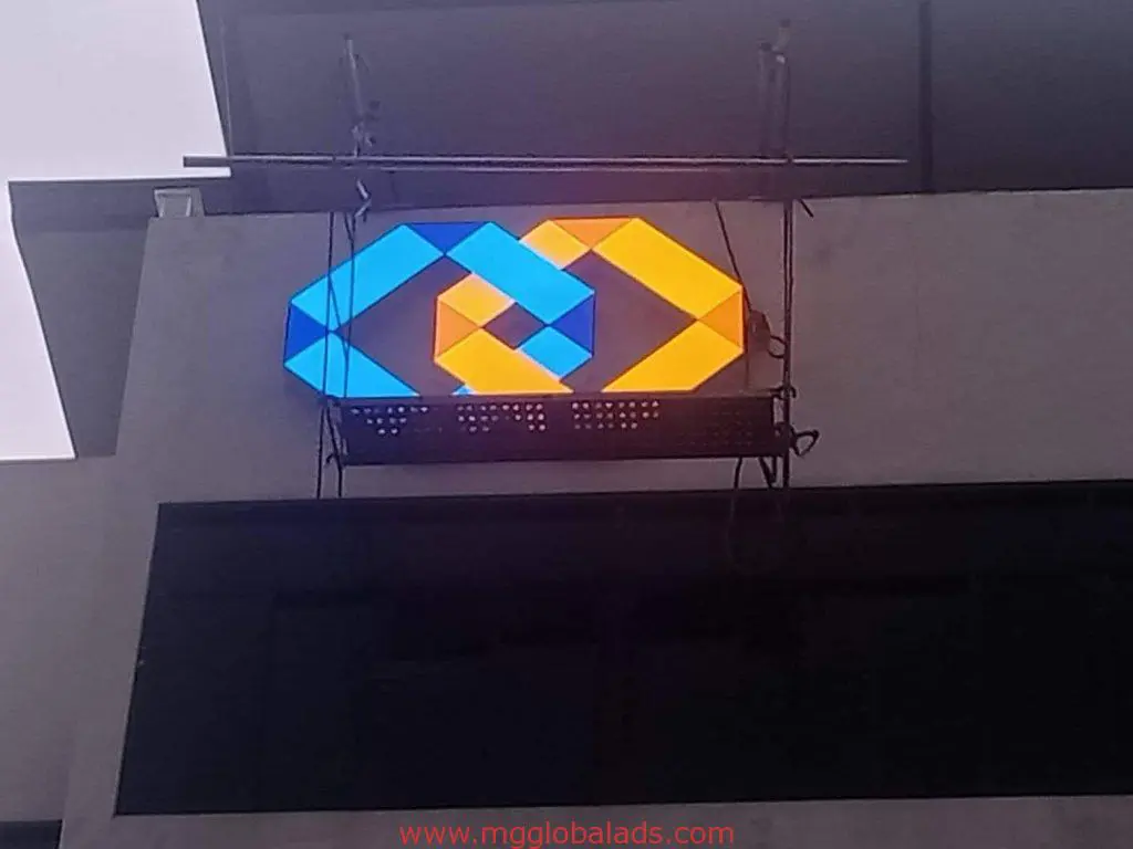 Geometric outdoor building signage with blue and yellow interlocking shapes in Makati, held by metal frame by M&G Global Ads.