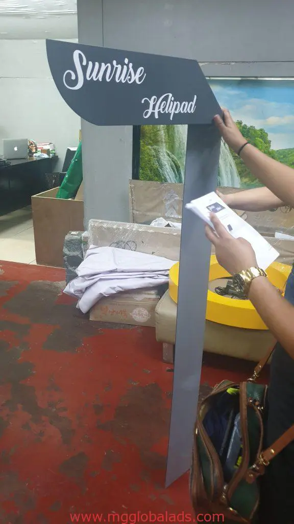 Acrylic speech bubble signage for Sunrise Helipad held by person, red floor and mural in Mandaluyong. By M&G Global Ads.