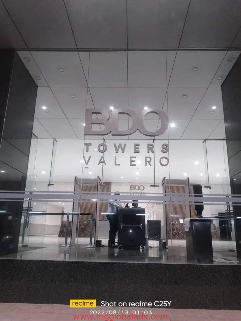 Sleek acrylic signage for BDO Towers Valero in Makati lobby, photographed indoors with a security guard by M&G Global Ads.