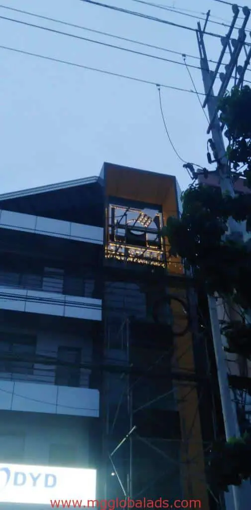 Modern building with LED signage and scaffolding in Quezon City at dusk, power lines visible—by M&G Global Ads.